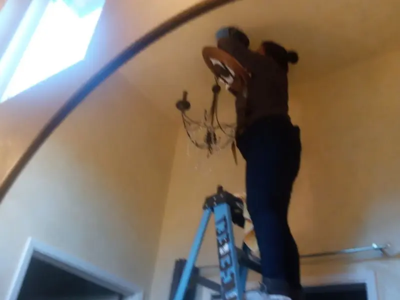 Electrician installing a chandelier in a Waterford residence